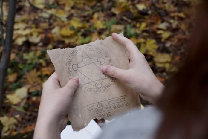 Mãos segurando um pergaminho com símbolos enigmáticos, representando mistérios históricos como o Código Voynich.