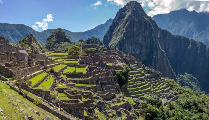 Vista panorâmica de Machu Picchu, a Cidade Perdida dos Incas, com suas ruínas e terraços agrícolas cercados por montanhas majestosas.