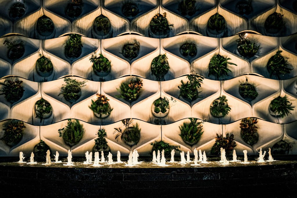 Parede vertical de plantas iluminada à noite, representando uma interpretação moderna dos Jardins Suspensos da Babilônia.