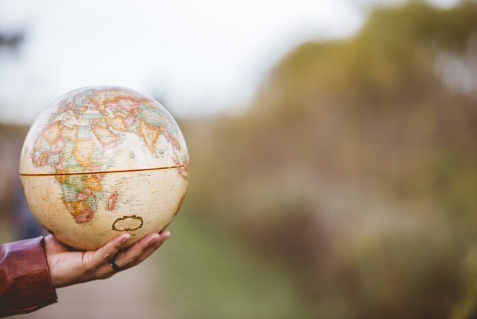 Globo terrestre sendo segurado por uma mão, representando a relação entre o planeta e os sons misteriosos do hum global.