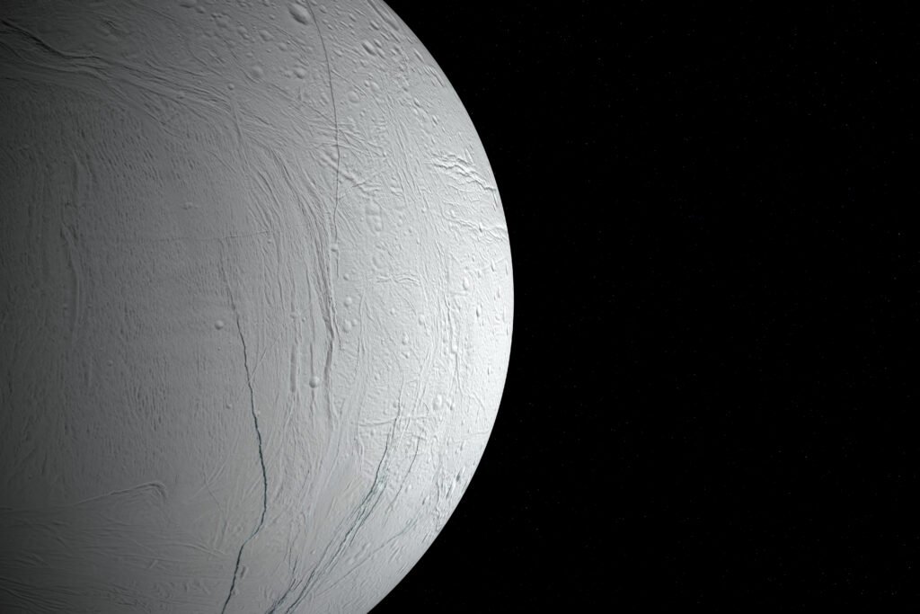 Superfície de Enceladus com detalhes de fissuras e cristas contra o espaço profundo.